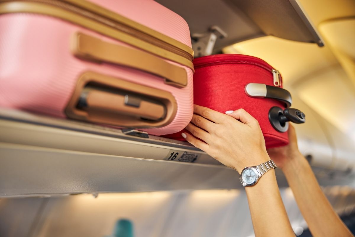 Bagagem de mão sendo colocada no compartimento superior do avião