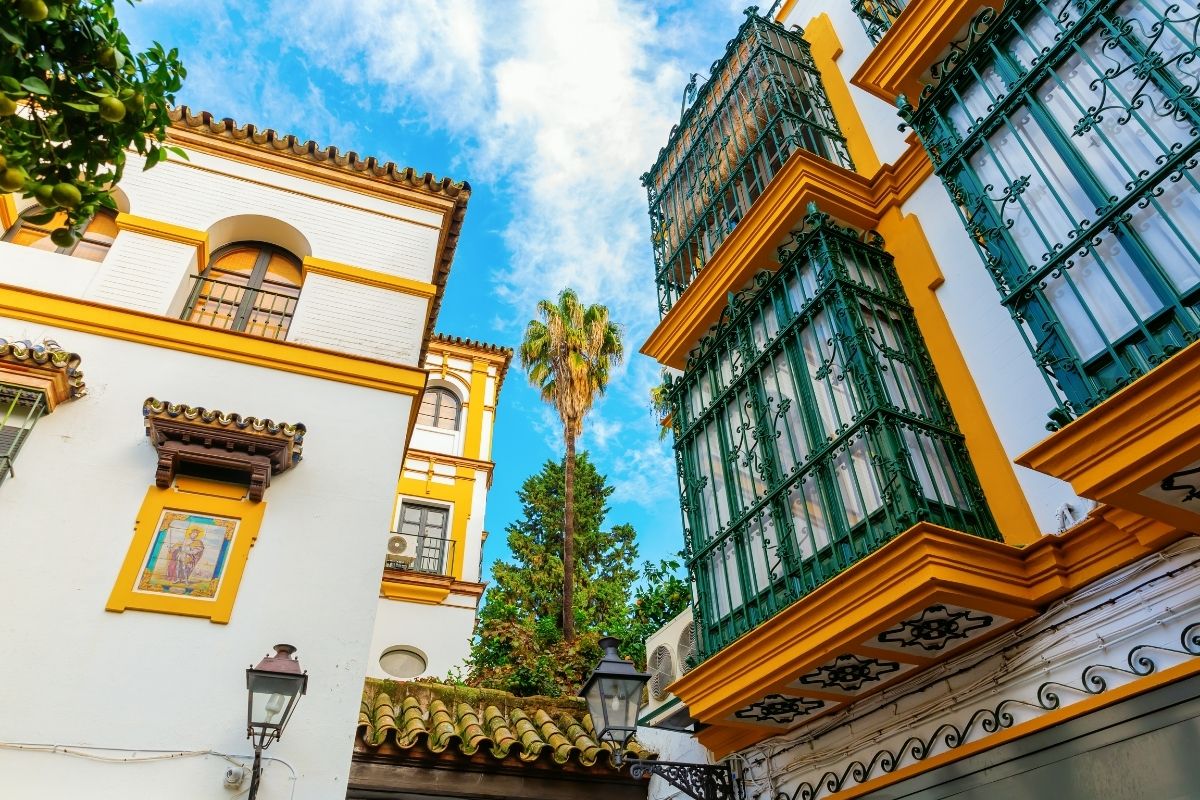 Casas brancas com detalhe amarelo e verde, de arquitetura tradicional de Sevilha, no bairro de Santa Cruz.