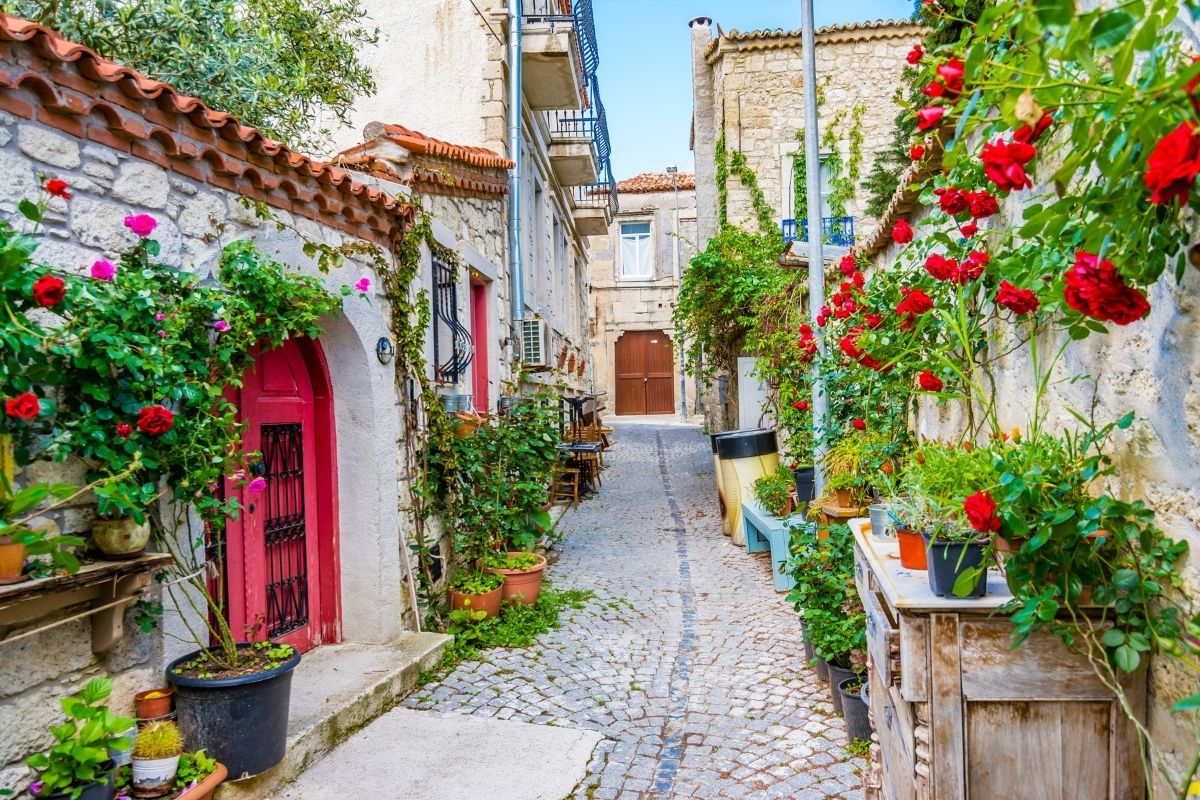 Rua estreita cheia de flores e casas de pedras em Alaçati