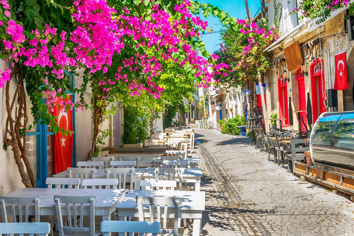 Rua de Alaçati com mesas de restaurante na calçada