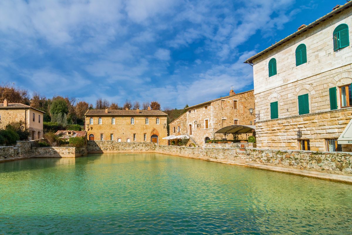 Piscina de água termal cercada por casarões medievais no Bagno Vignoni