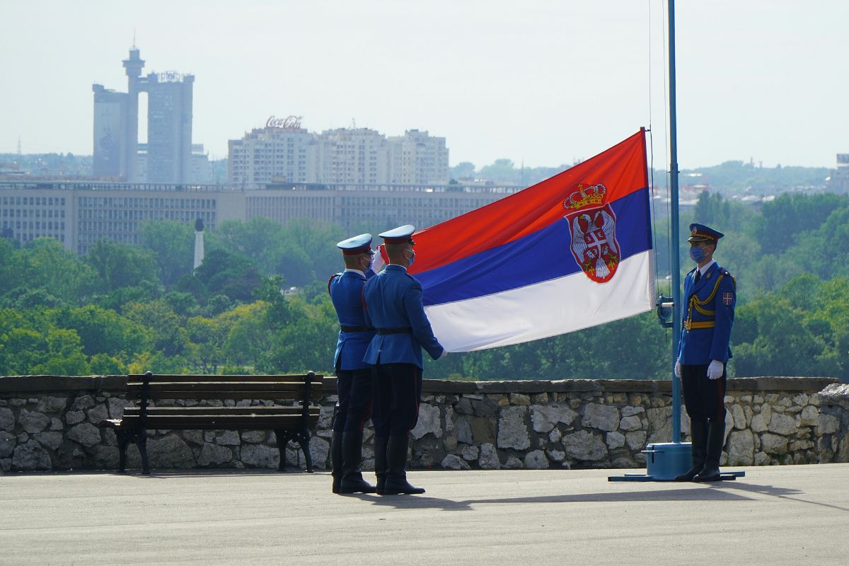 Homens hasteando bandeira da Sérvia
