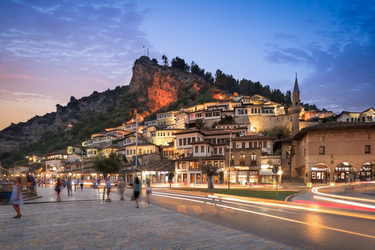 Pessoas caminhando à noite em cidade albanesa