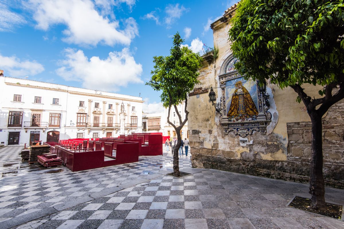 Praça de Jerez de la Frontera, na Espanha, com imagem de uma santa católica em destaque em um moro de um edifício histórico.
