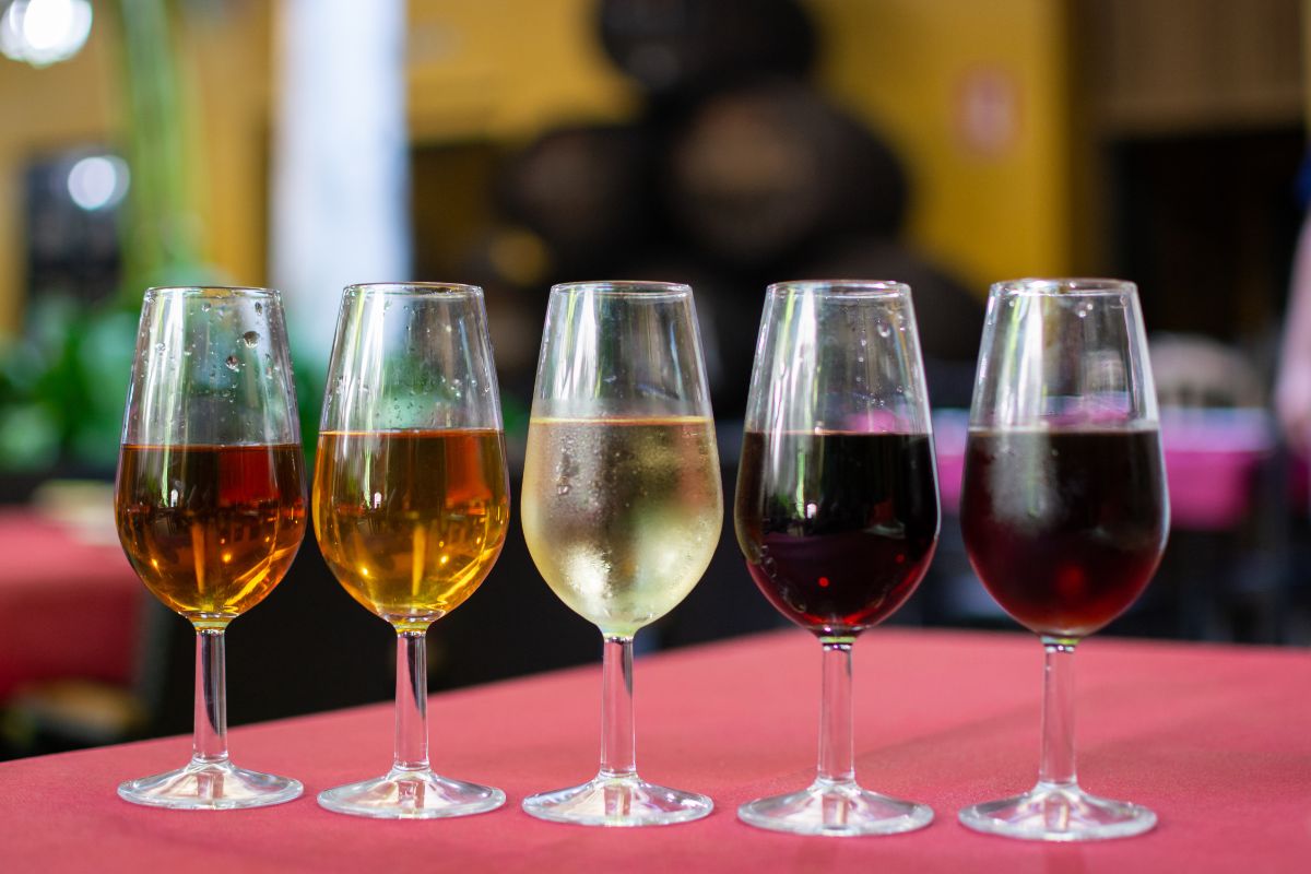Cinco taças servidas com diferentes tipos de vinho jerez para uma sessão de degustação em uma bodega.