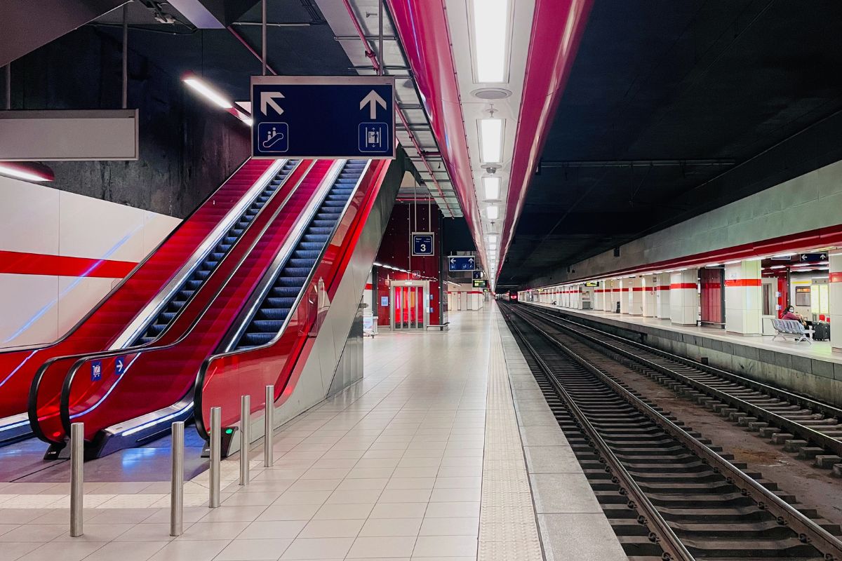 Plataforma da estação de trem localizada dentro do aeroporto de Bruxelas com trilho do trem e escadas rolantes