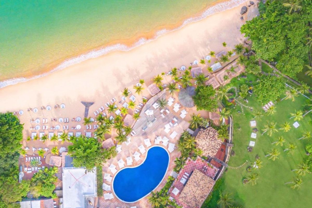 Vista aérea do hotel DPNY Beach Hotel & SPA, em Ilhabela, de frente para a praia, com piscina e espreguiçadeiras