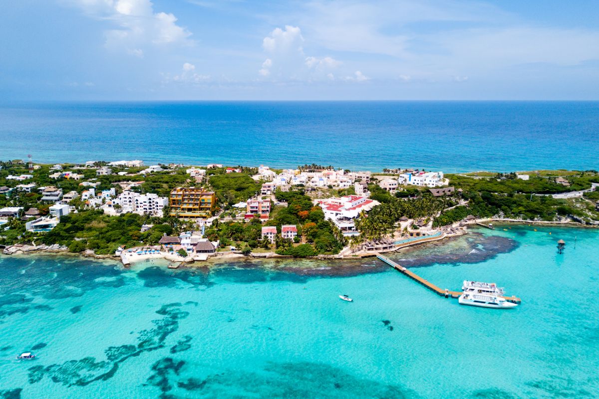 Vista aérea de Isla Mujeres, ilha no México, com infraestrutura hoteleira, píer e barcos, além de mar de cor azul claro