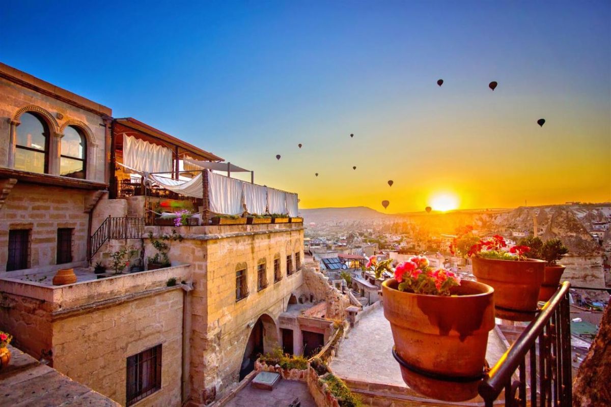 Terraço de hotel em Goreme com vista para o horizonte ao nascer do sol e com balões voando ao fundo