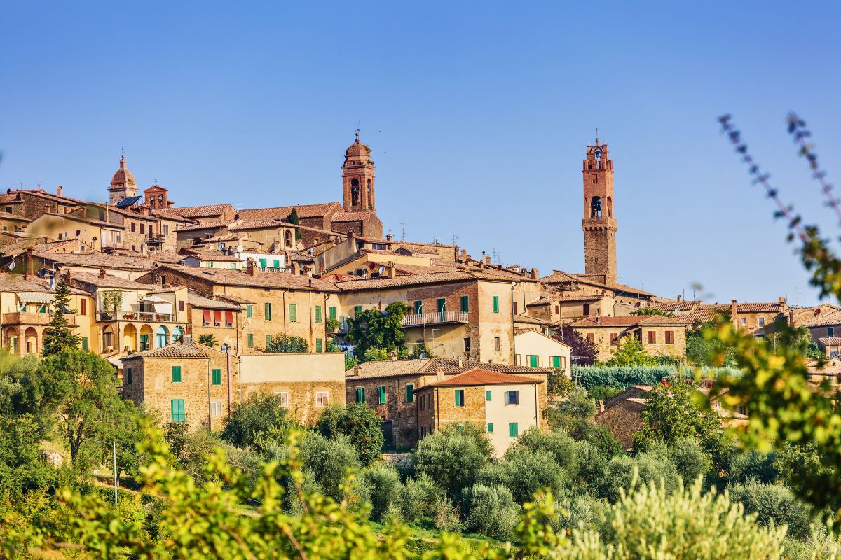 Vilarejo medieval de Montalcino, no Val d'Orcia, em cima de uma colina, rodeado pela natureza e com construções medievais preservadas de tons terrosos e janelas verdes