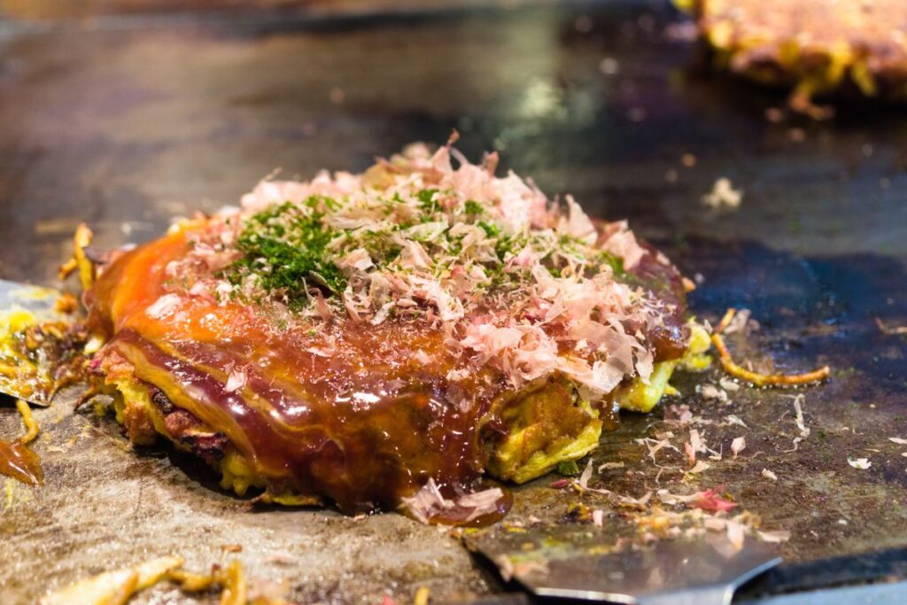 Finalização de um okonomiyaki em uma chapa quente