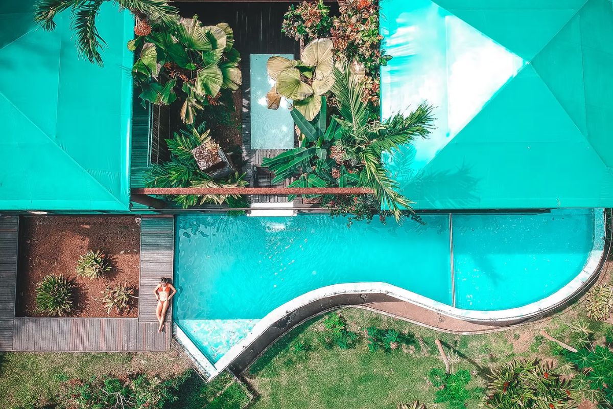 Foto aérea de mulher tomando sol ao lado de piscina