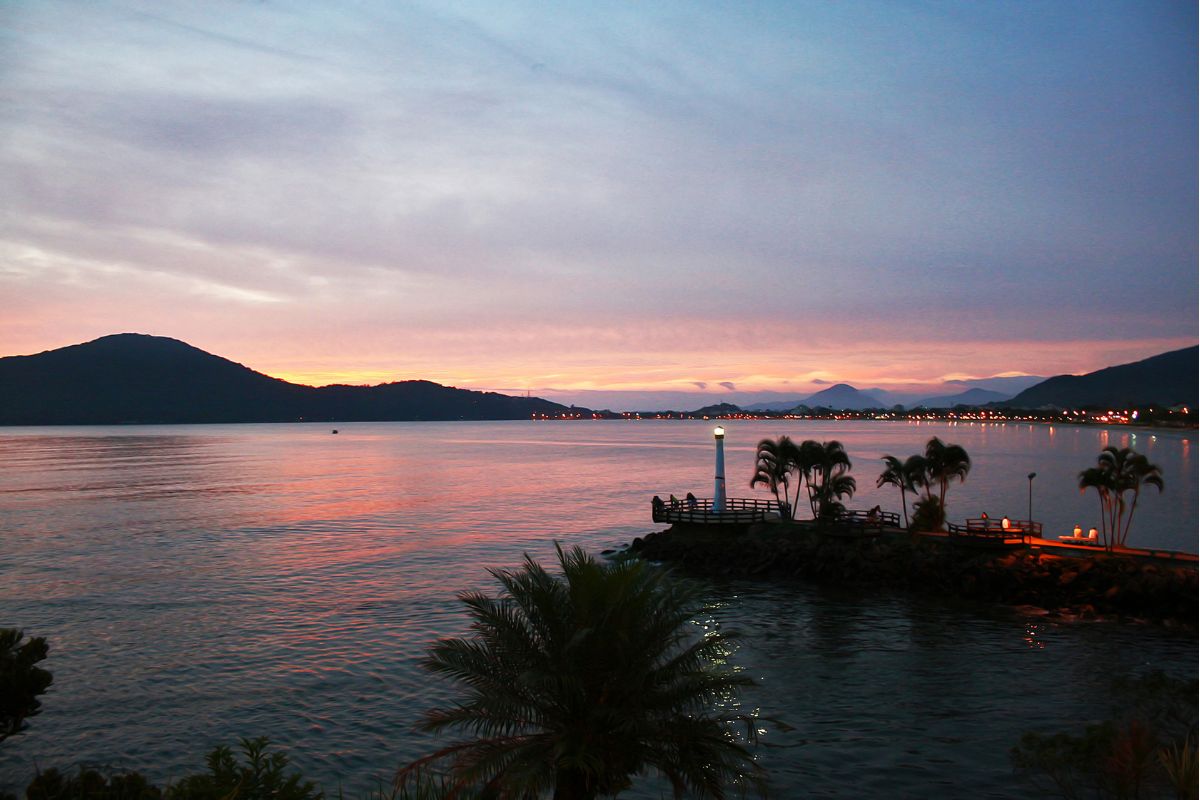 Baía de Ubatuba ao entardecer com as luzes da cidade ao fundo começando a se acender