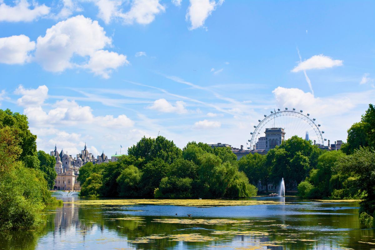 Parque St. James com grande lafo a frente, cercado por área verde e, ao fundo, parte da roda gigante London Eye