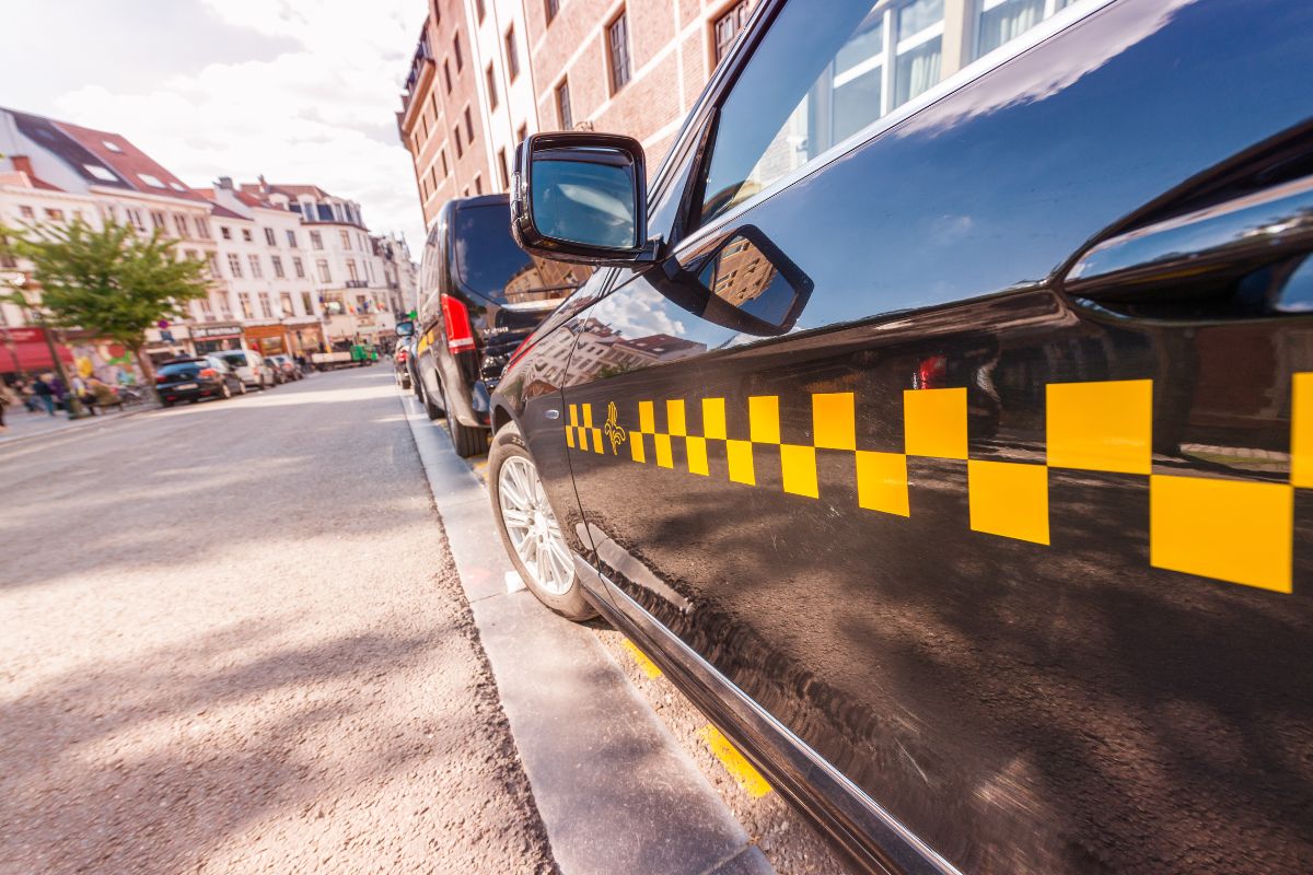 Táxi de Bruxelas preto com detalhes amarelo estacionado na rua da cidade