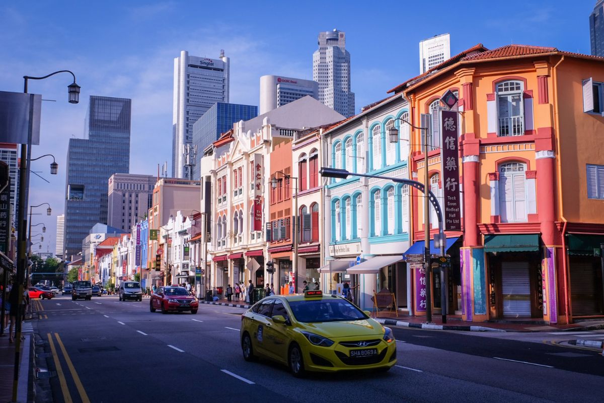 Táxia amarelo circulando em rua de Singapura