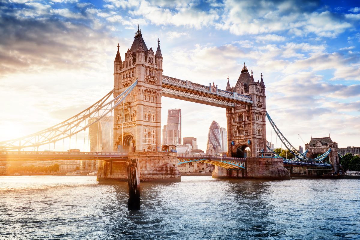 Ponte de Londres no pôr do sol com edifícios modernos ao fundo e rio Tâmisa a frente