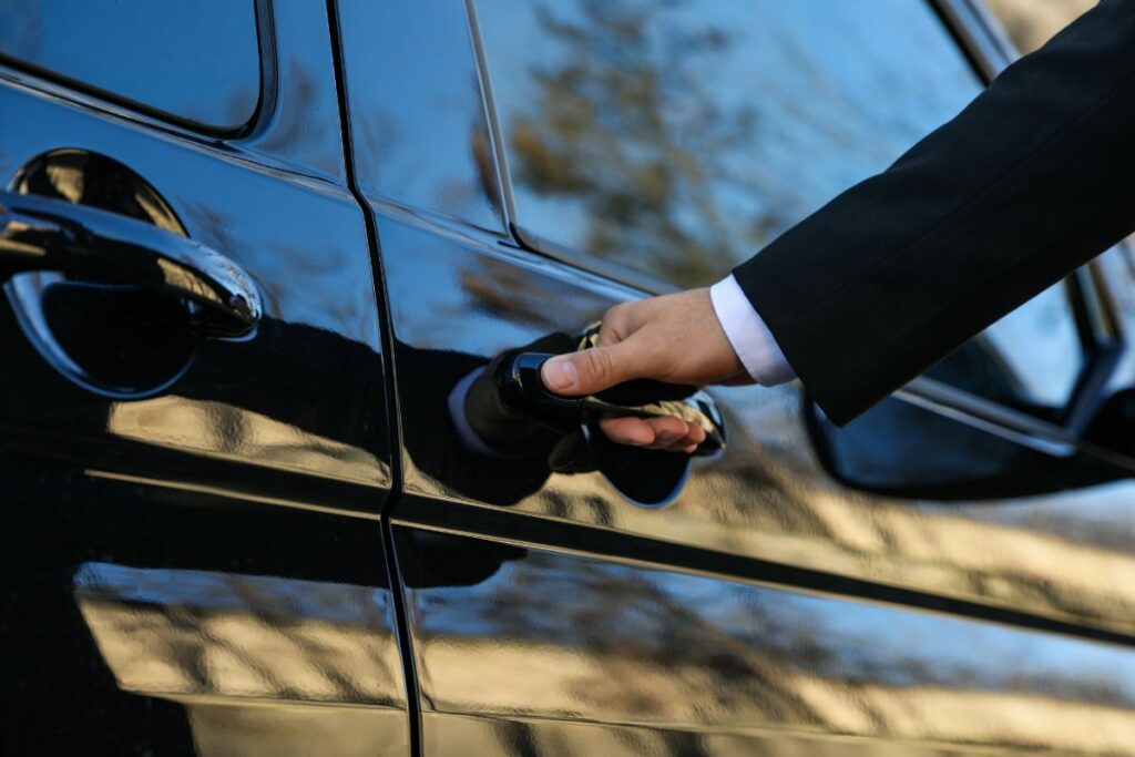 Motorista de transfer privativo abrindo a porta do carro para um passageiro