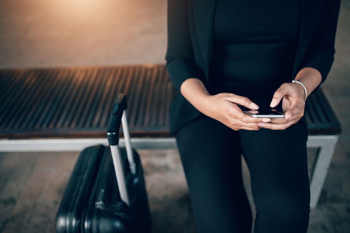 Mulher no aeroporto solicitando carro por aplicativo